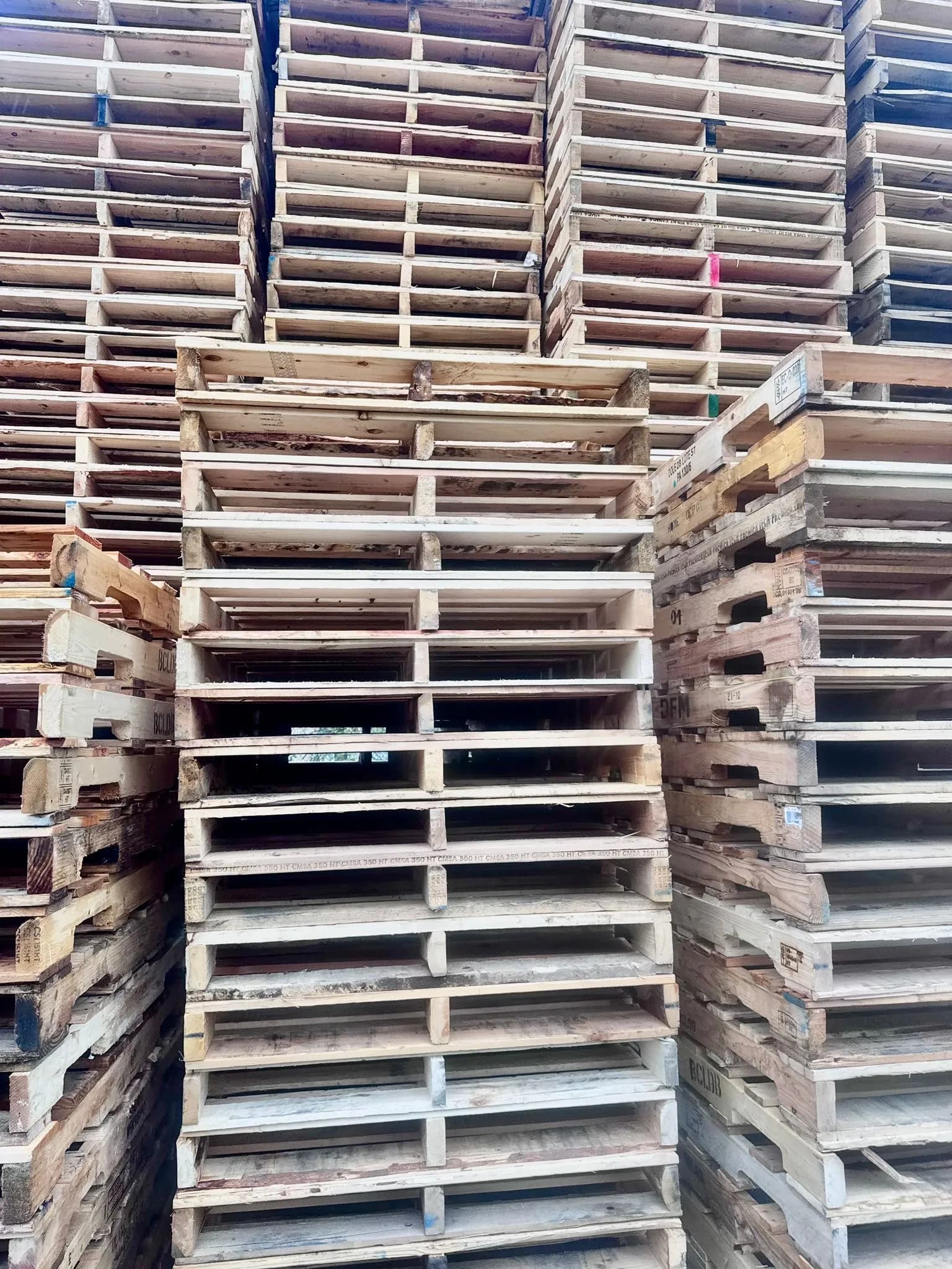 Large inventory of stacked wooden pallets in outdoor storage yard