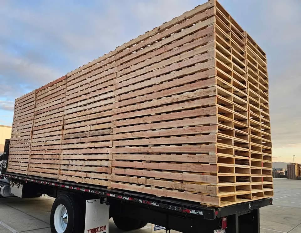 New wooden pallets stacked high on a flatbed truck at sunset